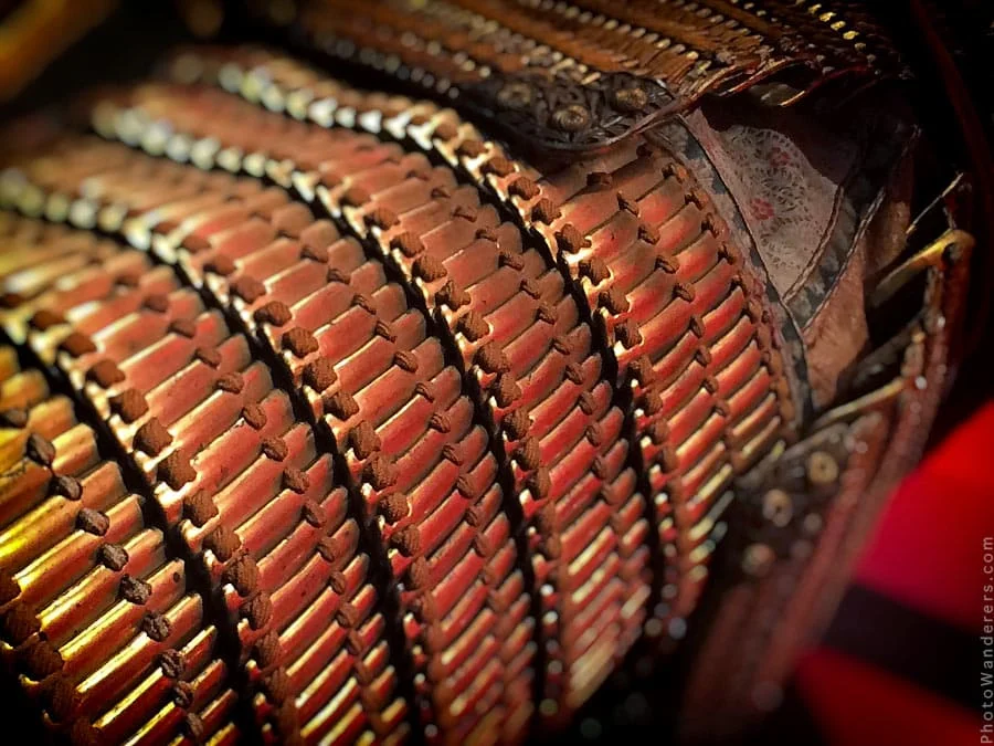 The plates up close. Hundreds of them, laced in rows by hand — hundreds of hours of work in what looks like texture.