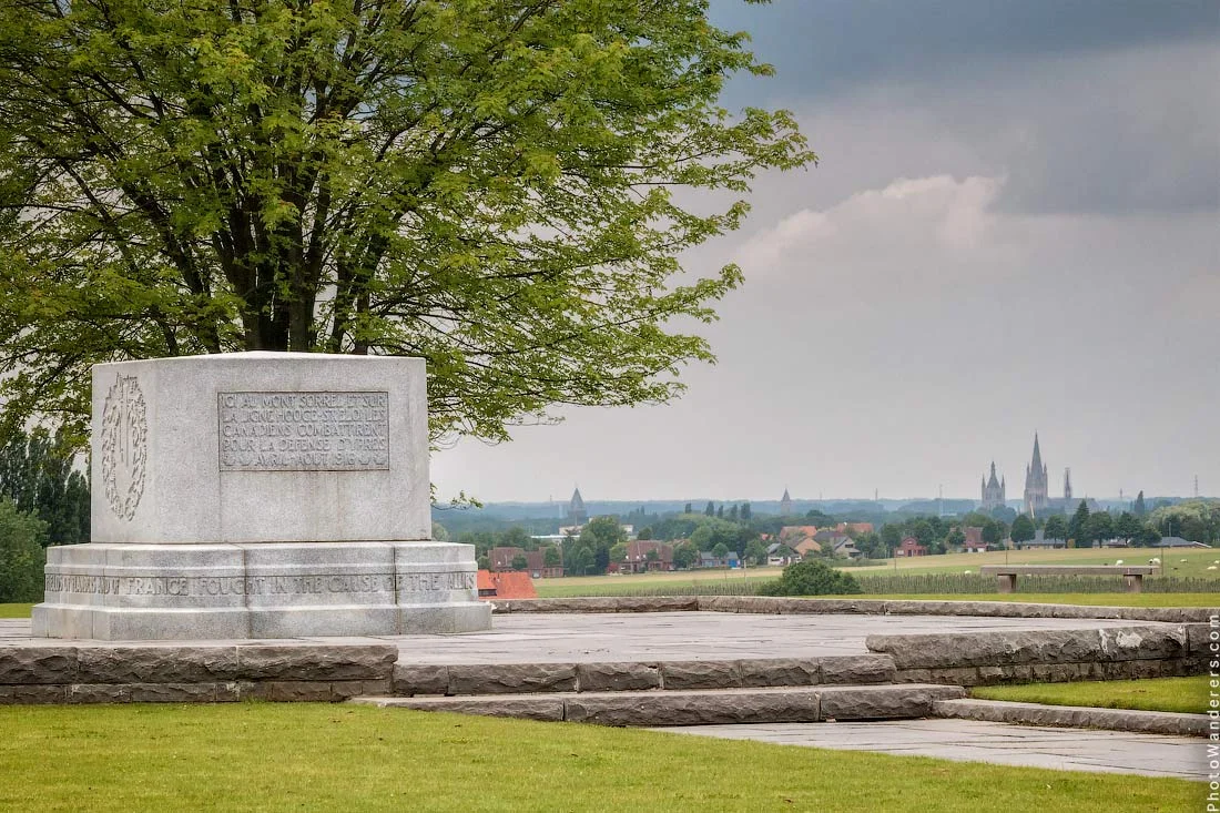 From the memorial fields, the towers of Ypres stand small and pale on the horizon.