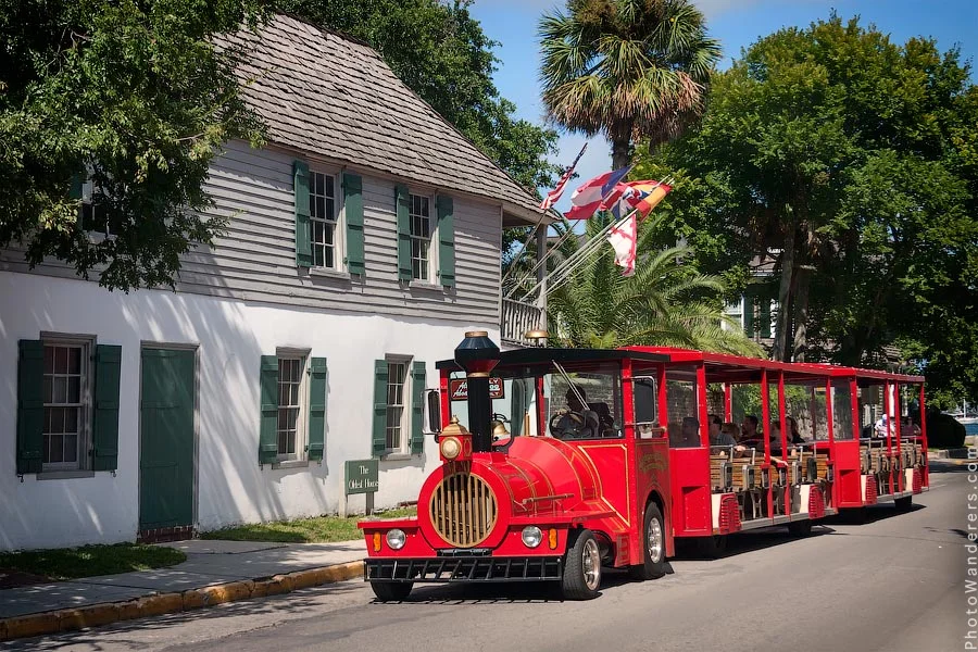 Red tourist tram passing the Oldest House in St. Augustine