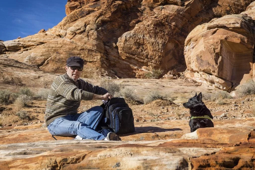Jack on a swooping red rock shelf, looking back at Alex